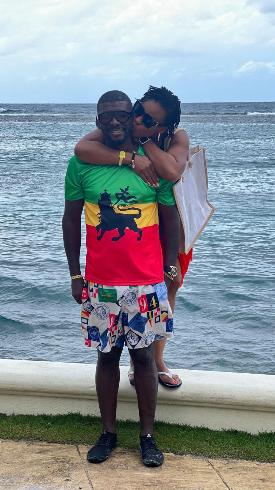 Sylvia hugging Edmund from behind by the ocean