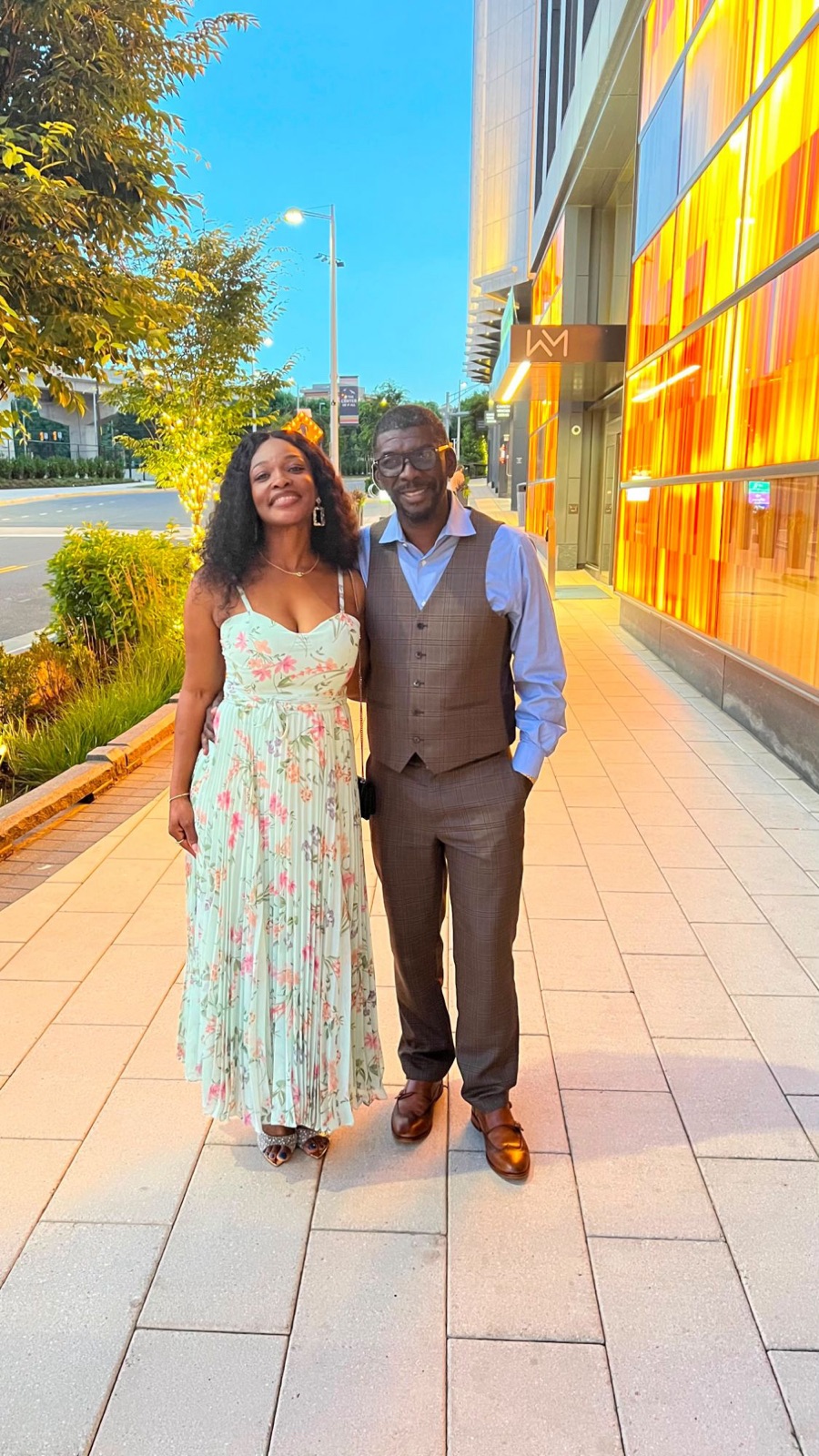 Edmund and Sylvia smiling together on a city sidewalk at golden hour